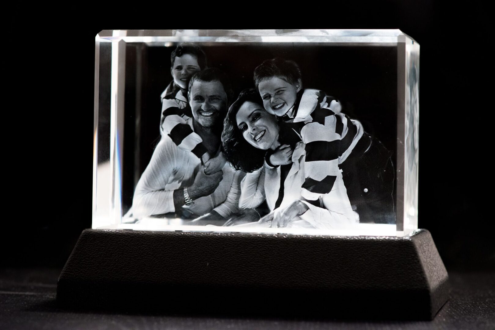A 3D crystal engraving of a happy family with two children.